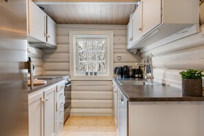 A compact kitchen with wooden walls, a window with frosted glass, and modern appliances. - FA674- 5 Bedrooms, Private Sauna and Ski Access (Trysil)