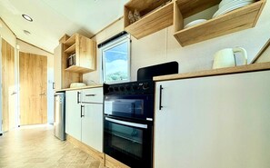 Eine Küche mit Holzausstattung, einem Einbauofen und einem Fenster über der Spüle.