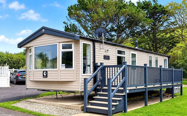 A single-story mobile home with a front deck and a staircase leading to the entrance. - The Loire - Luxury Retreat by the Sea in Devon (Challaborough)