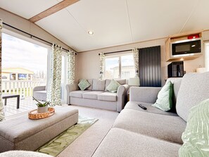 A cozy living room with a sofa, a coffee table, and a TV mounted on the wall.