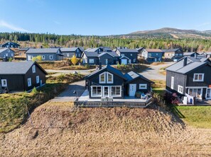 A residential area with multiple houses, a prominent house with a porch, and a hilly landscape in the background. - GV19– Family-Friendly Cabin at Trysilfjellet Arena (Trysil)