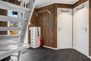 A corner room with a white door, a white bench, a white cabinet with drawers, a red fire extinguisher, and a wooden wall. - GV19– Family-Friendly Cabin at Trysilfjellet Arena (Trysil)