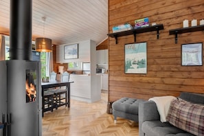 A cozy cabin interior with a wood-burning stove, a dining area, and a living room with a sofa. - AV47 Prime Ski-In/Ski-Out Location in Trysil (Trysil)