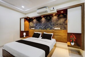 Une chambre d’hôtel moderne dotée d’un grand lit, d’une tête de lit en bois, d’un climatiseur et d’un panneau décoratif mural.