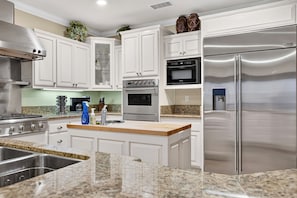 A modern kitchen with white cabinetry, stainless steel appliances, a granite countertop, and a built-in oven. - Game Room + Covered Decks + Fire Pit • Near Lake Arrowhead | Wooded Wonder (Lake Arrowhead)