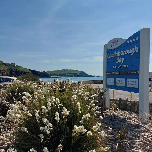 A sign for Chablborough Bay Holiday Park with amenities listed including direct beach access, indoor pool complex, restaurant, and showbar.