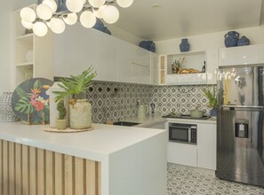 A modern kitchen with white cabinetry, a stainless steel refrigerator, and a patterned backsplash. - The Leaf Eco Villa (Vy Da)
