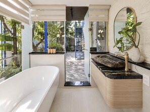 A modern bathroom with a bathtub, a sink with a marble countertop, and a large mirror. - The Leaf Eco Villa (Vy Da)