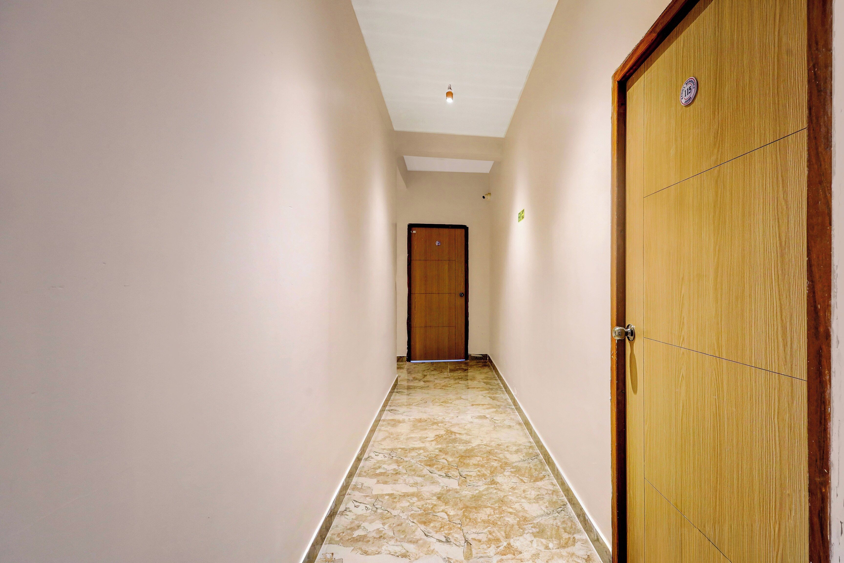 A narrow hallway with a wooden door on the right and a closed door at the end.