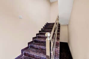 A staircase with a handrail and a light switch on the wall.