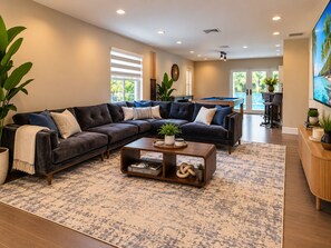 Una sala de estar moderna con un sofá modular, una mesa de centro y una mesa de billar.