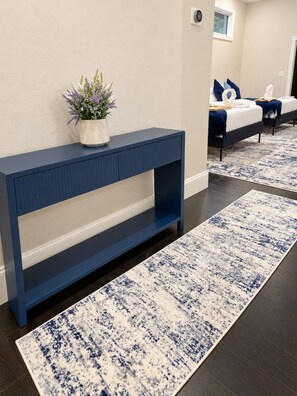 A modern room with a dark blue console table, a white potted plant, and a blue and white patterned rug.