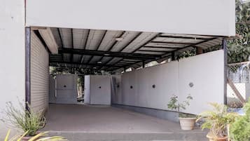 An open-air covered parking area with concrete flooring and metal roofing.