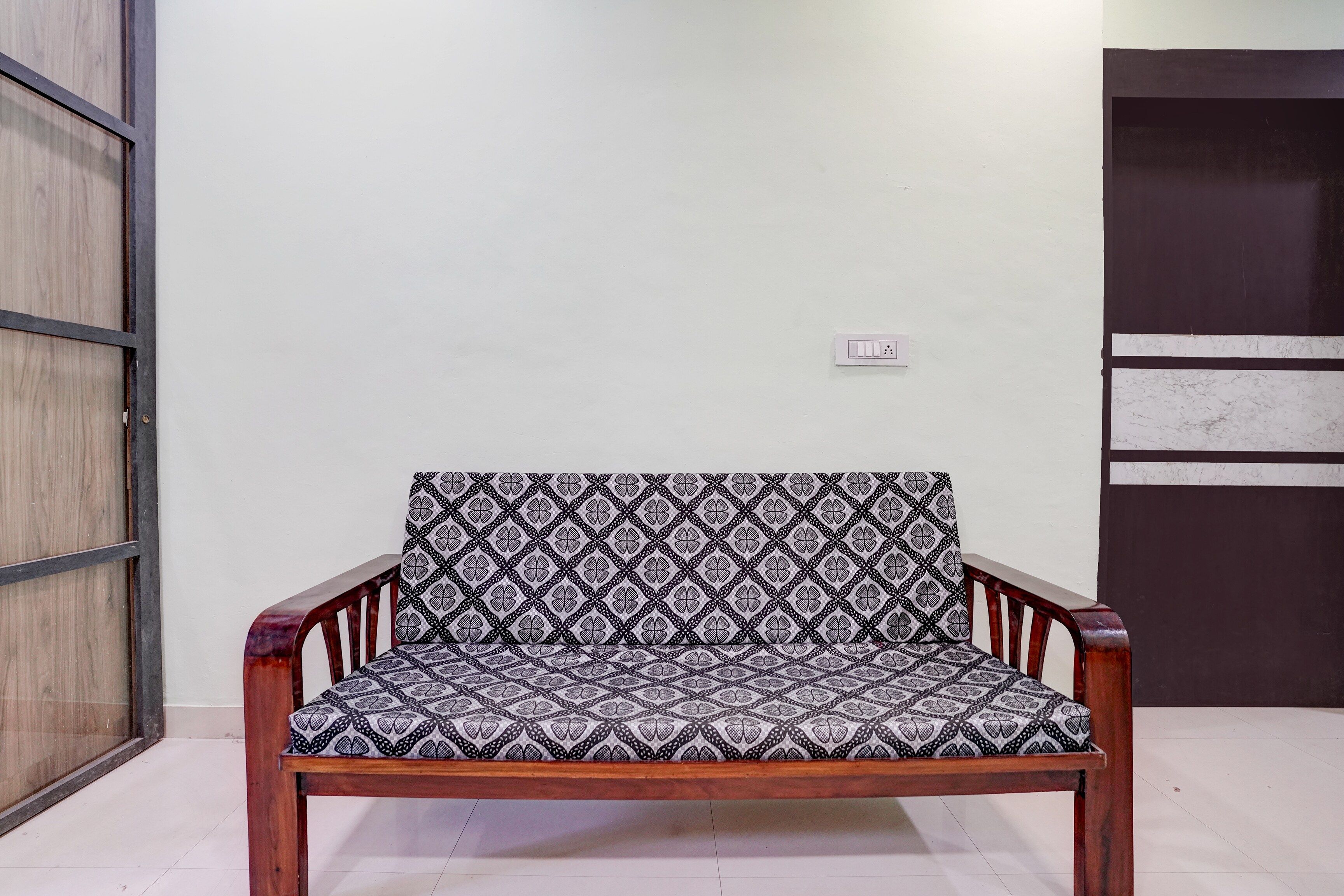 A wooden chair with a patterned cushion in a room with a white wall and a door.