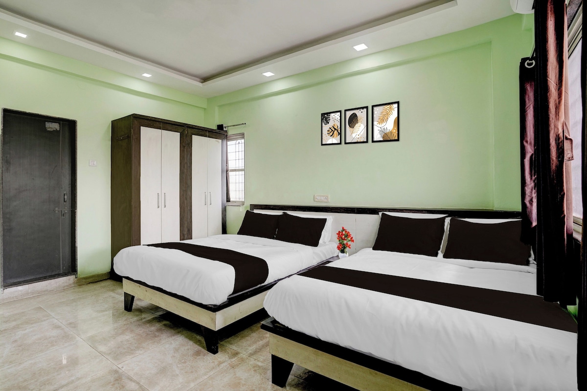 A hotel room with two beds, a wardrobe, and a window.