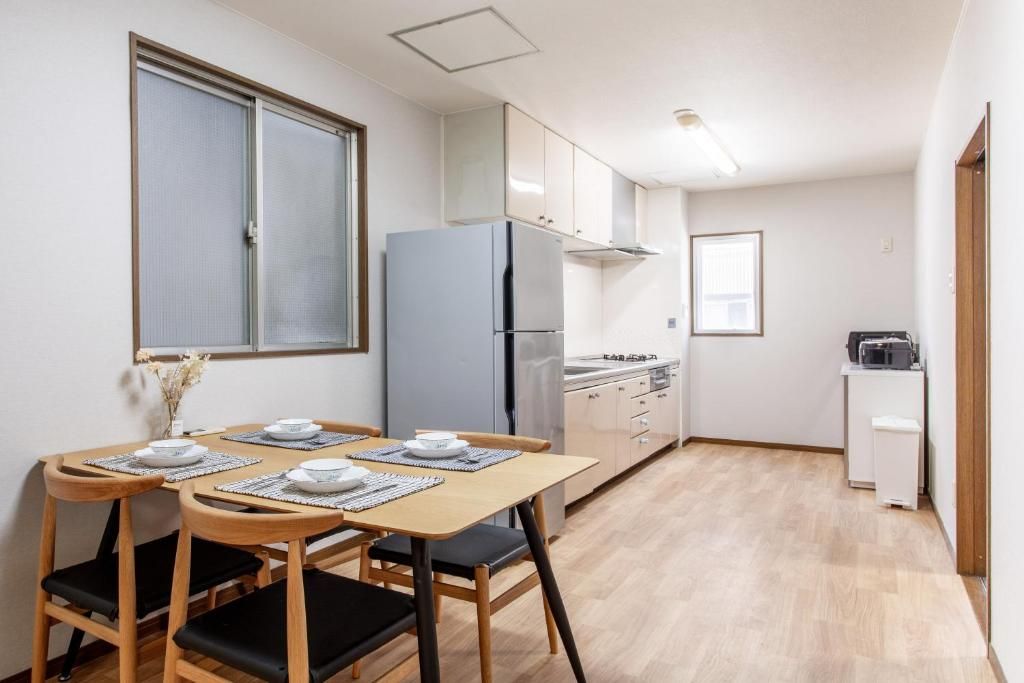 A compact kitchen with a dining table set for two, a refrigerator, and a microwave.