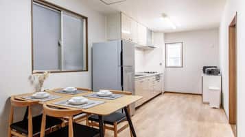 A compact kitchen with a dining table set for two, a refrigerator, and a microwave.