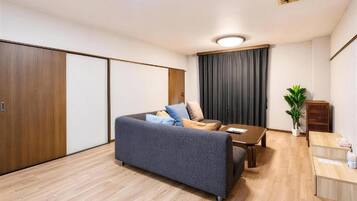 A modern living room with a sofa, a coffee table, and a small dining area.