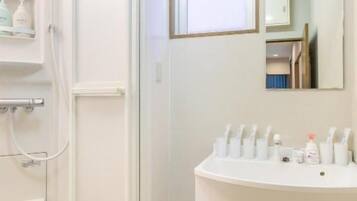 A bathroom with a shower, a sink, and a mirror.