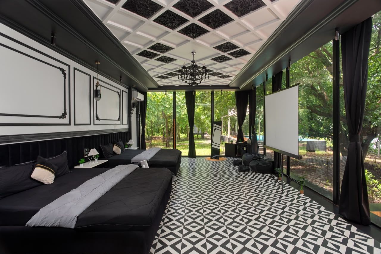 Habitación de hotel con dos camas, una pantalla de proyector y un ventanal con vistas a zonas verdes.