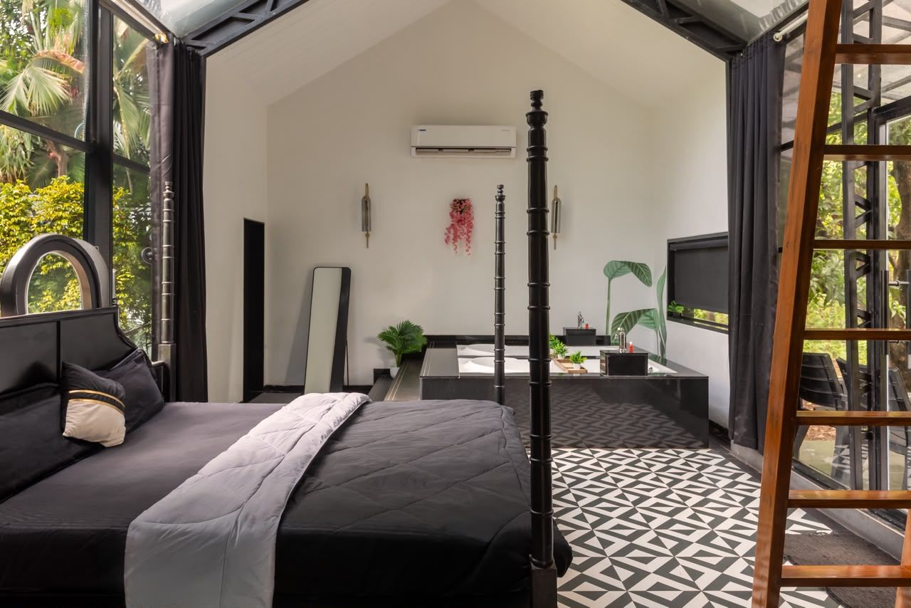 A modern bedroom with a bed, a bedside table, a TV, and a balcony with a view of greenery.