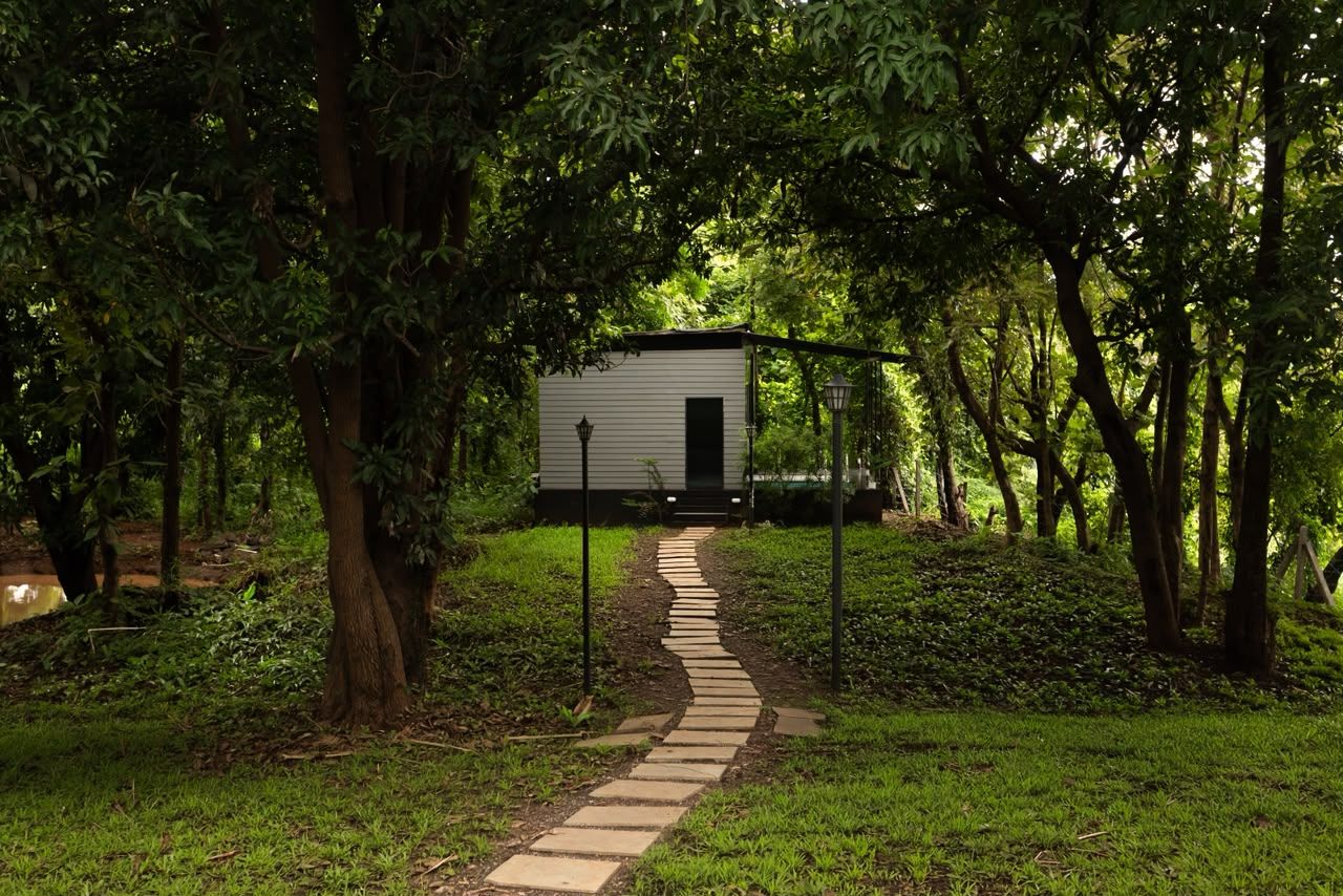 A pathway leading to a small, single-story building surrounded by dense greenery.