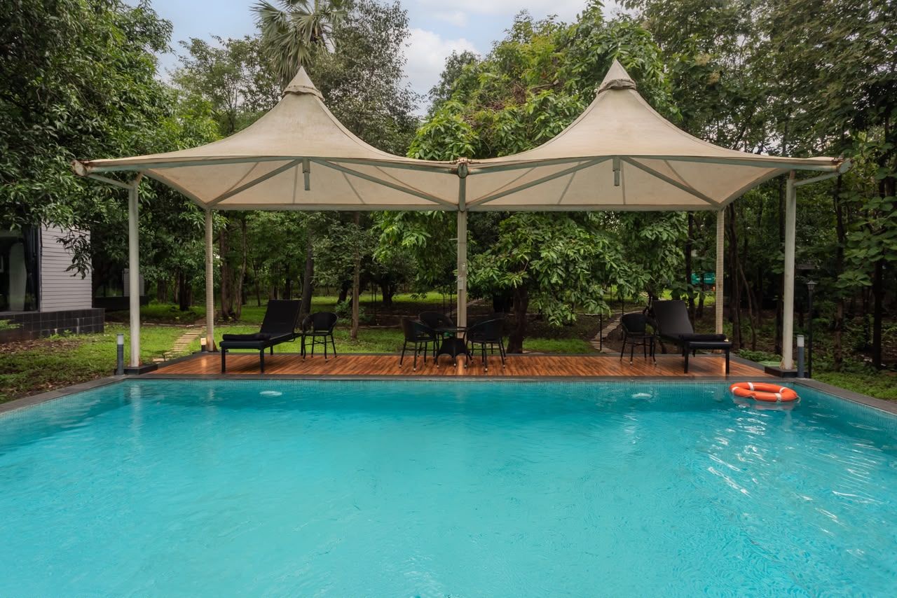 Una piscina con una sombrilla, rodeada de sillas y un flotador.