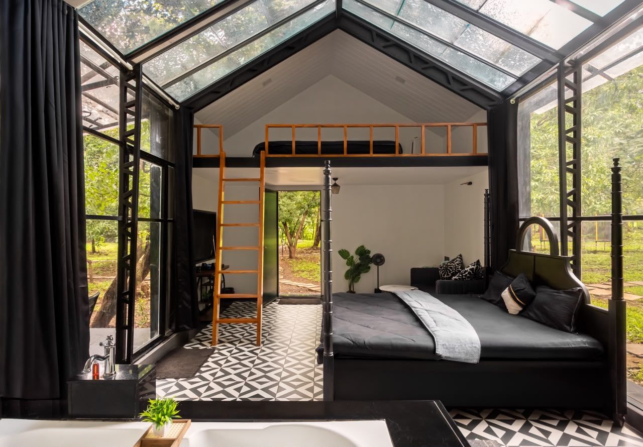 A modern bedroom with a skylight, a bunk bed, a bedside table, and a view of greenery.