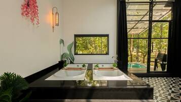 A bathroom with a large window, two sinks, and a view of a pool.