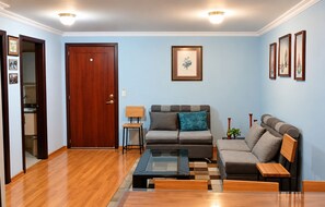 A living room with a wooden floor, a sofa, a coffee table, and a door. - 3-bedroom apartment in welcoming Quito (Quito)