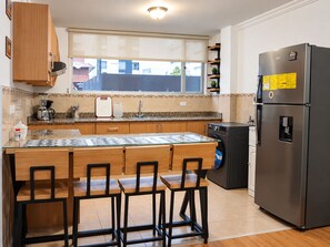 A compact kitchen with a built-in island, a refrigerator, and a washing machine. - 3-bedroom apartment in welcoming Quito (Quito)