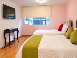 A hotel room with two beds, a TV on the wall, a window with a blind, and a small table with towels. - 3-bedroom apartment in welcoming Quito (Quito)