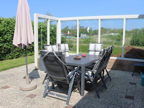 An outdoor patio with a table and chairs, a covered umbrella, and a view of the surrounding greenery. - Bungalow With 3 Bedrooms (Julianadorp)