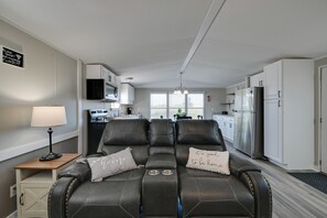 A modern living room with a sofa, a lamp, and a kitchen in the background. - Countryside Gem w/ Fire Pit: 14 Mi to Mammoth Cave (Brownsville)