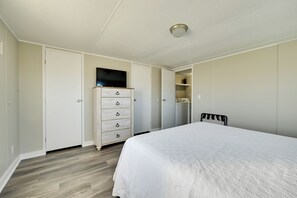 Quarto com cama, penteadeira, televisão e armário.
