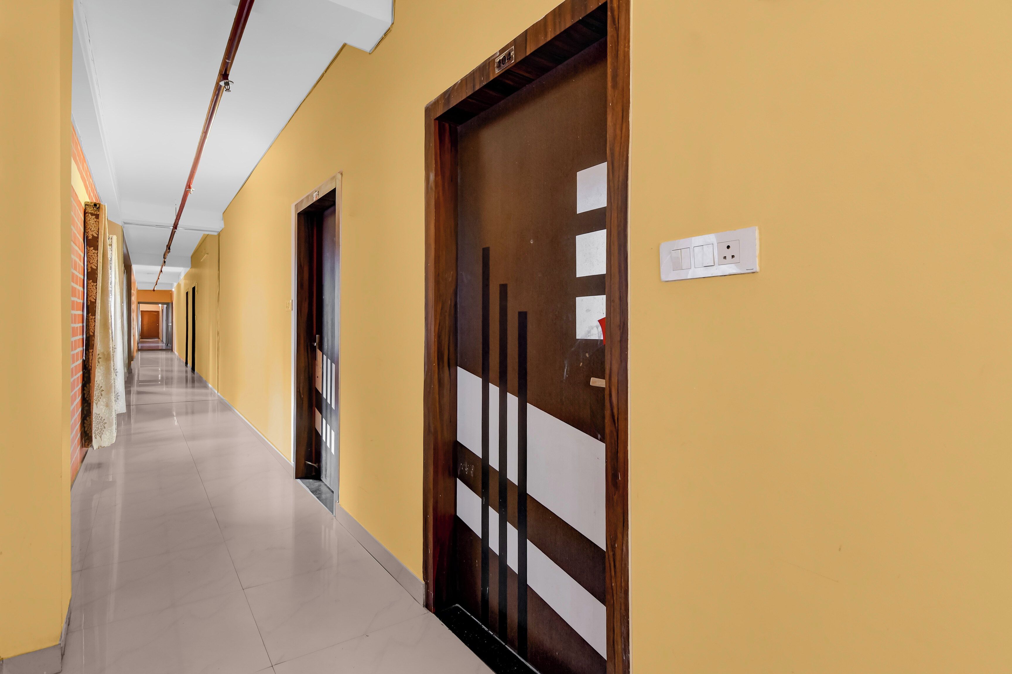 A corridor with doors, a light switch, and a tiled floor.