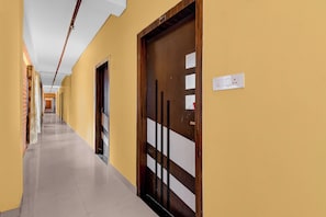 A corridor with doors, a light switch, and a tiled floor. - Townhouse Oak Siliguri (Siliguri)