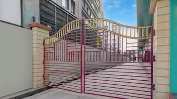 Una entrada protegida con un portón metálico y una escalera que lleva a un edificio.