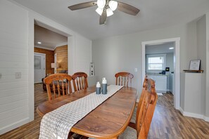 A dining room with a wooden table, chairs, a ceiling fan, and a kitchen in the background. - Fishing Pond! Quiet, Renovated Family Farmhouse! (Brownsville)