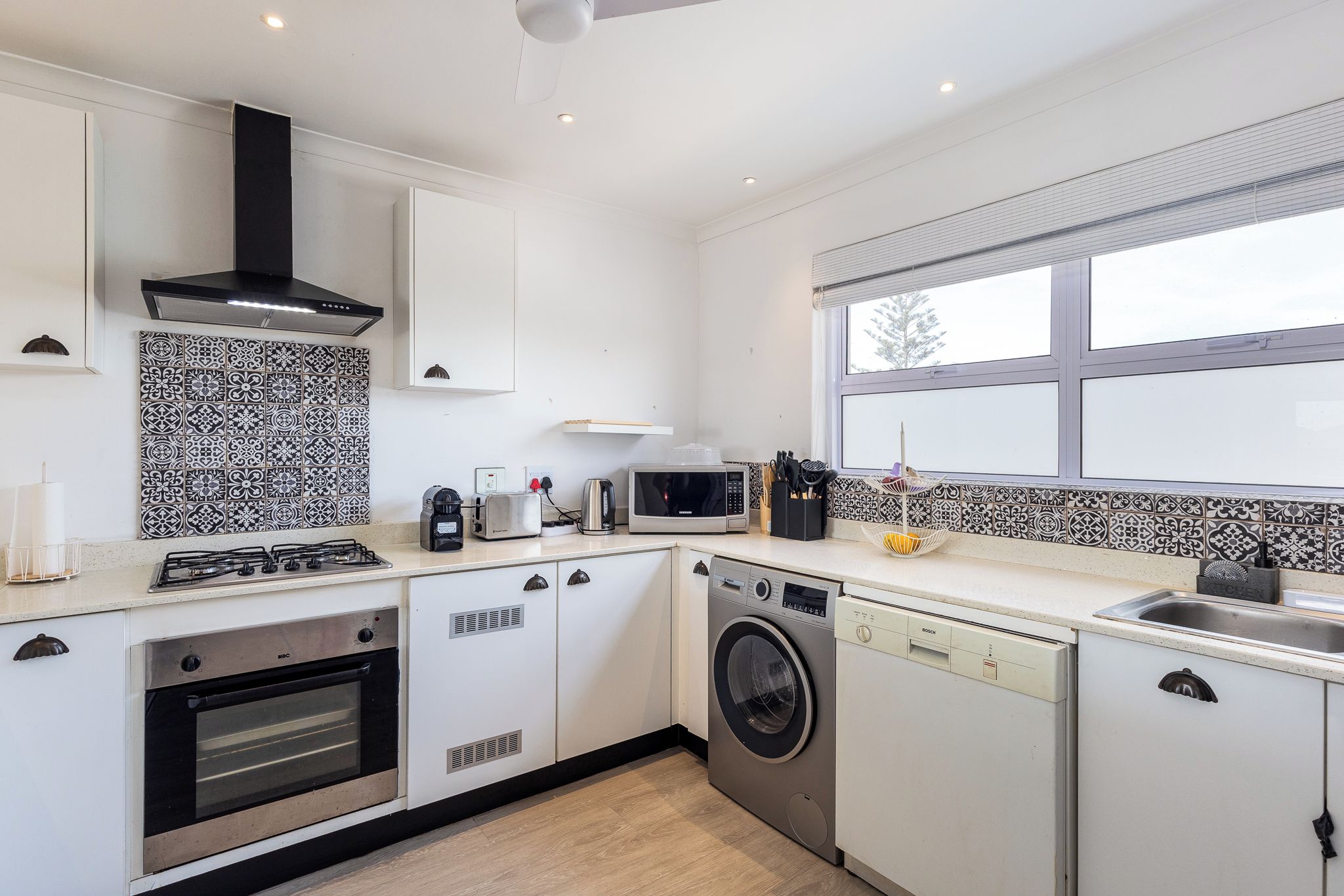 A modern kitchen with white cabinetry, a built-in oven, microwave, and dishwasher.