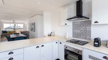 Une cuisine moderne avec des meubles blancs, une hotte noire et un pare-feu décoré.