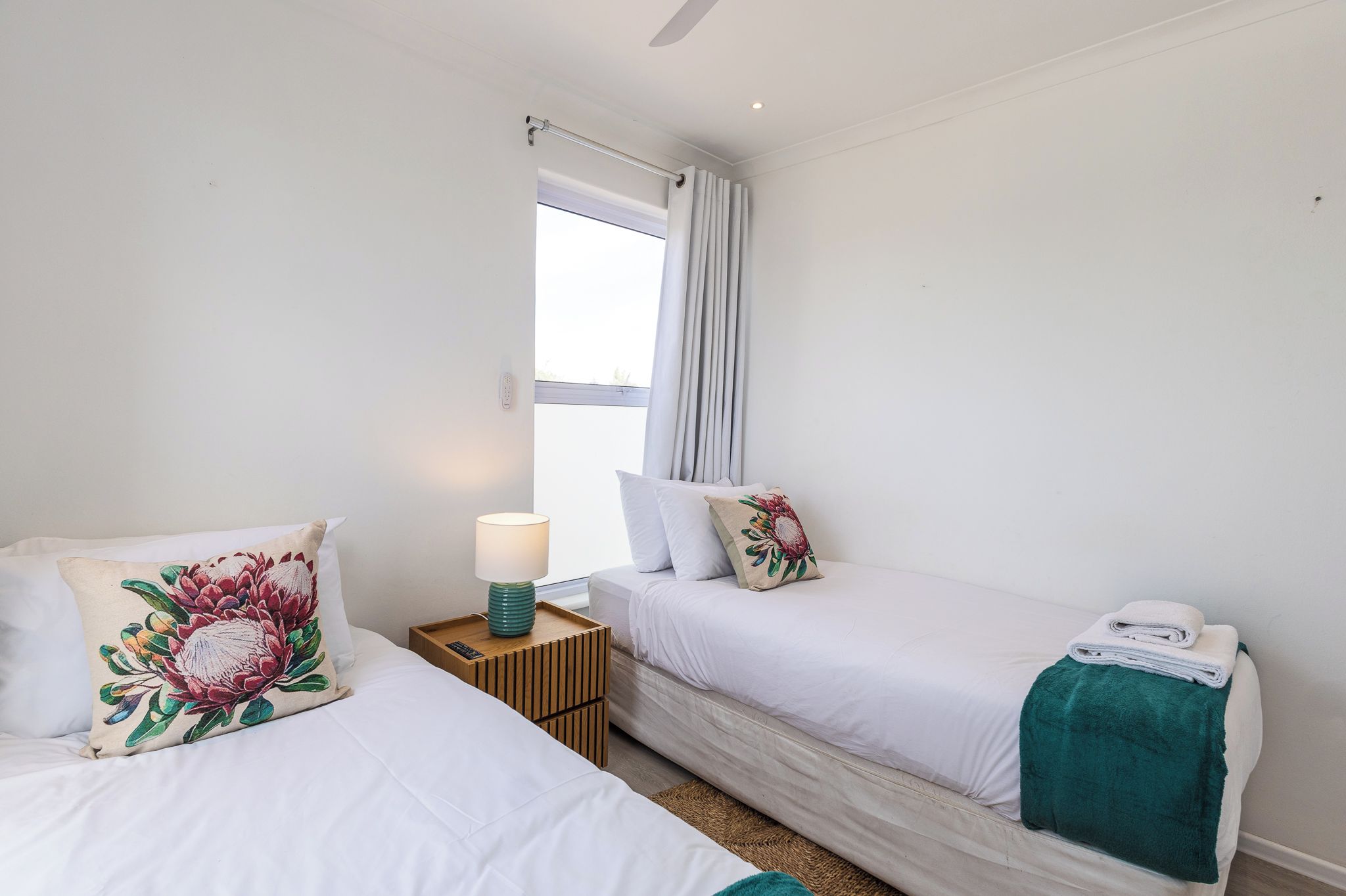 Une chambre d’hôtel avec deux lits, une table de chevet avec une lampe et une fenêtre avec des rideaux.