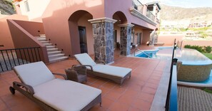 A poolside area with lounge chairs and a stone pillar. - PBMC · Pueblo Bonito Montecristo Owners Estate 3BR3B (Cabo San Lucas)