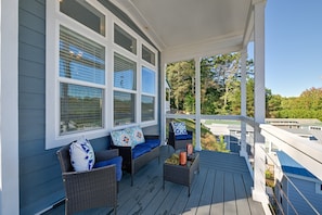 A covered porch with wicker furniture and a view of the surrounding area.