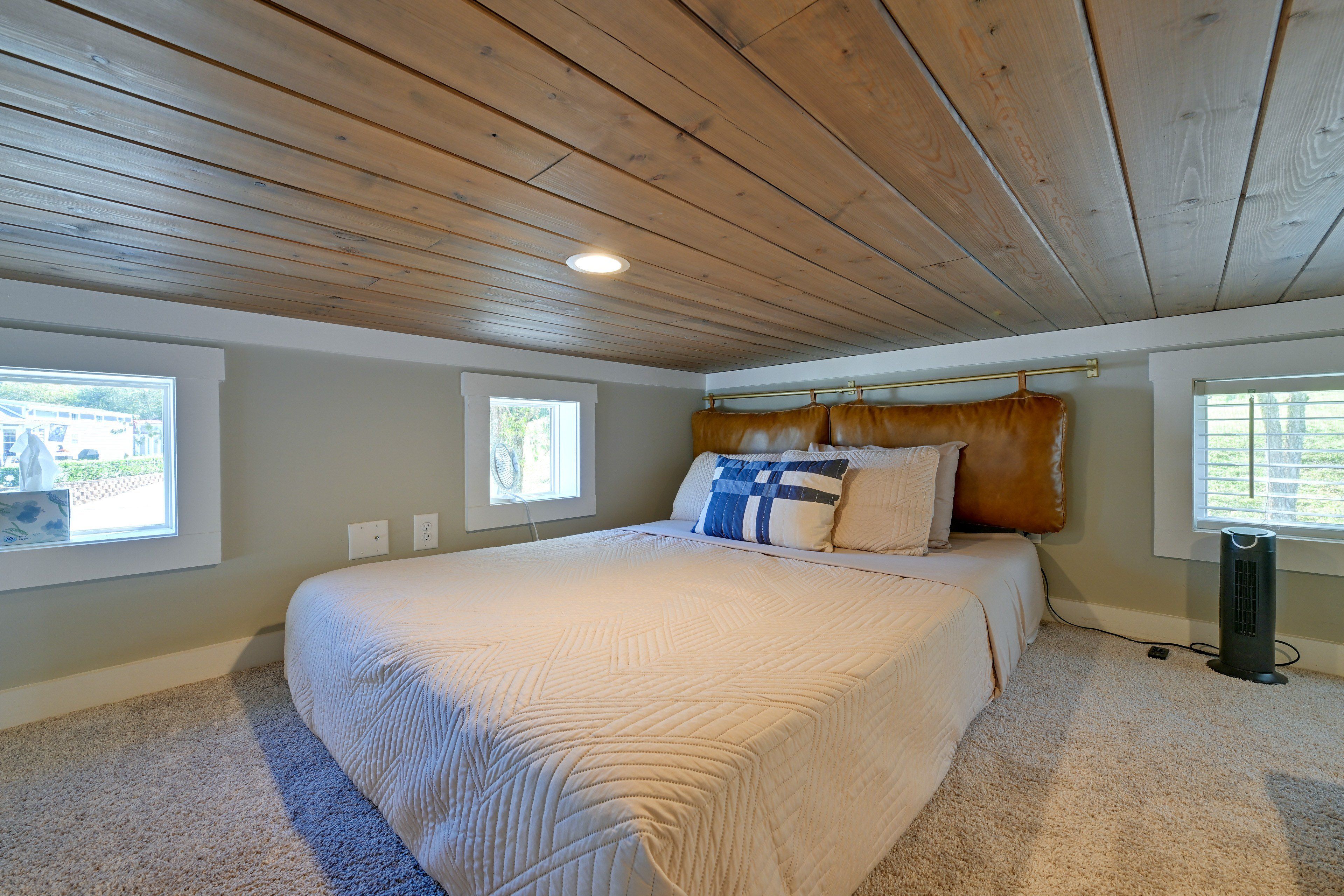 Ein Schlafzimmer mit einem großen Bett, zwei Fenstern, einem Deckenventilator und einem Heizgerät.