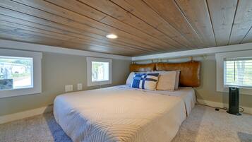 Ein Schlafzimmer mit einem großen Bett, zwei Fenstern, einem Deckenventilator und einem Heizgerät.