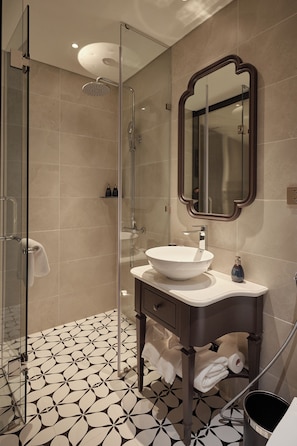 Un bany modern amb plat de dutxa de vidre, un lavabo sobre taulell i un mirall gran.