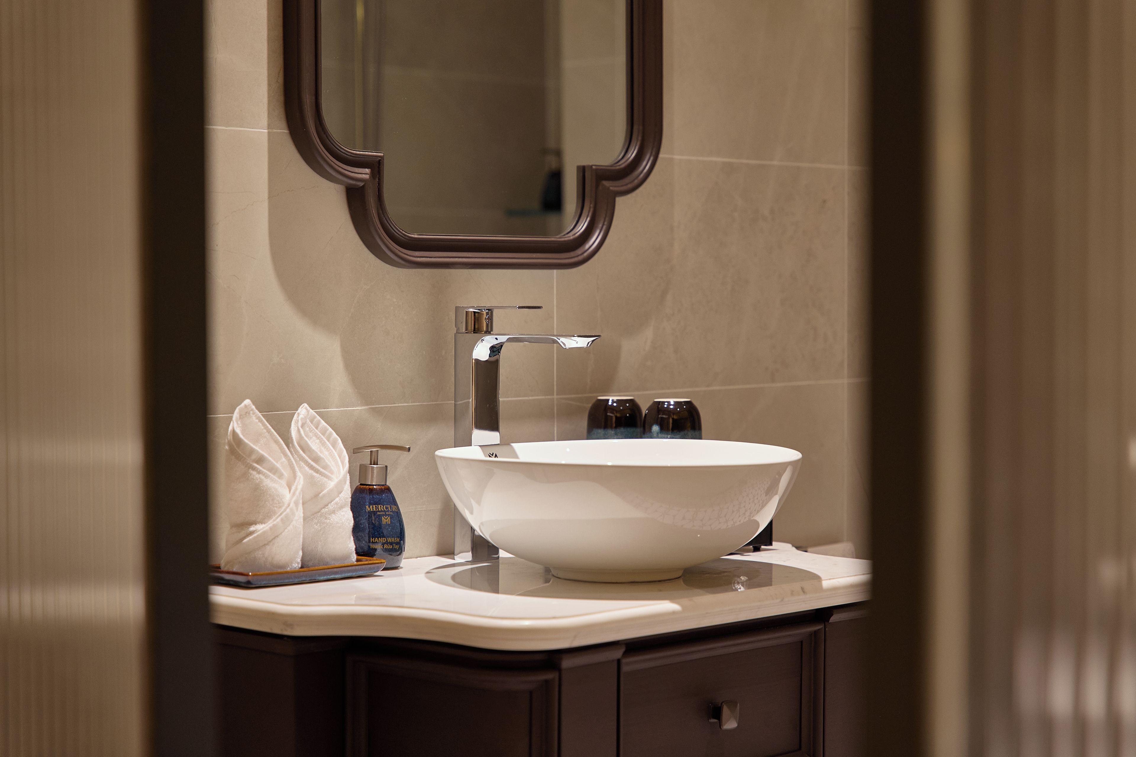 A bathroom with a white vessel sink, a mirror, and a towel.