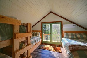 A cozy attic bedroom with wooden bunk beds, a large window, and a ceiling fan. - Hocking Hills Area Retreat: Relax & Explore! (Rockbridge)