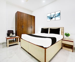 A bedroom with a bed, a wardrobe, a nightstand, a coffee table, and a wall-mounted picture. - Classic Maharaja Grand (New Delhi)